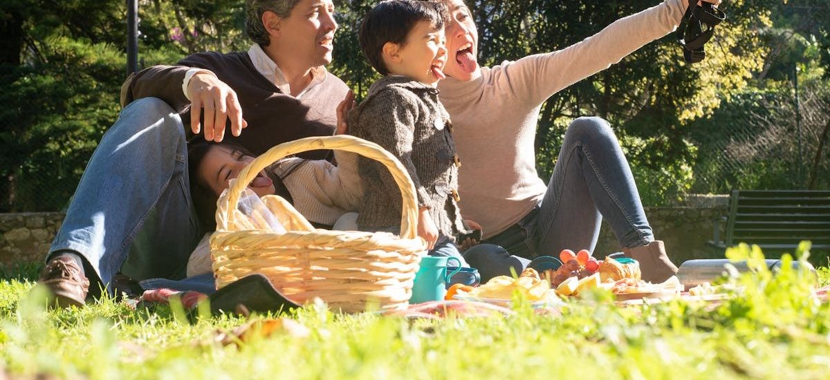 A happy family captures a selfie during a sunny picnic in a Portuguese park.